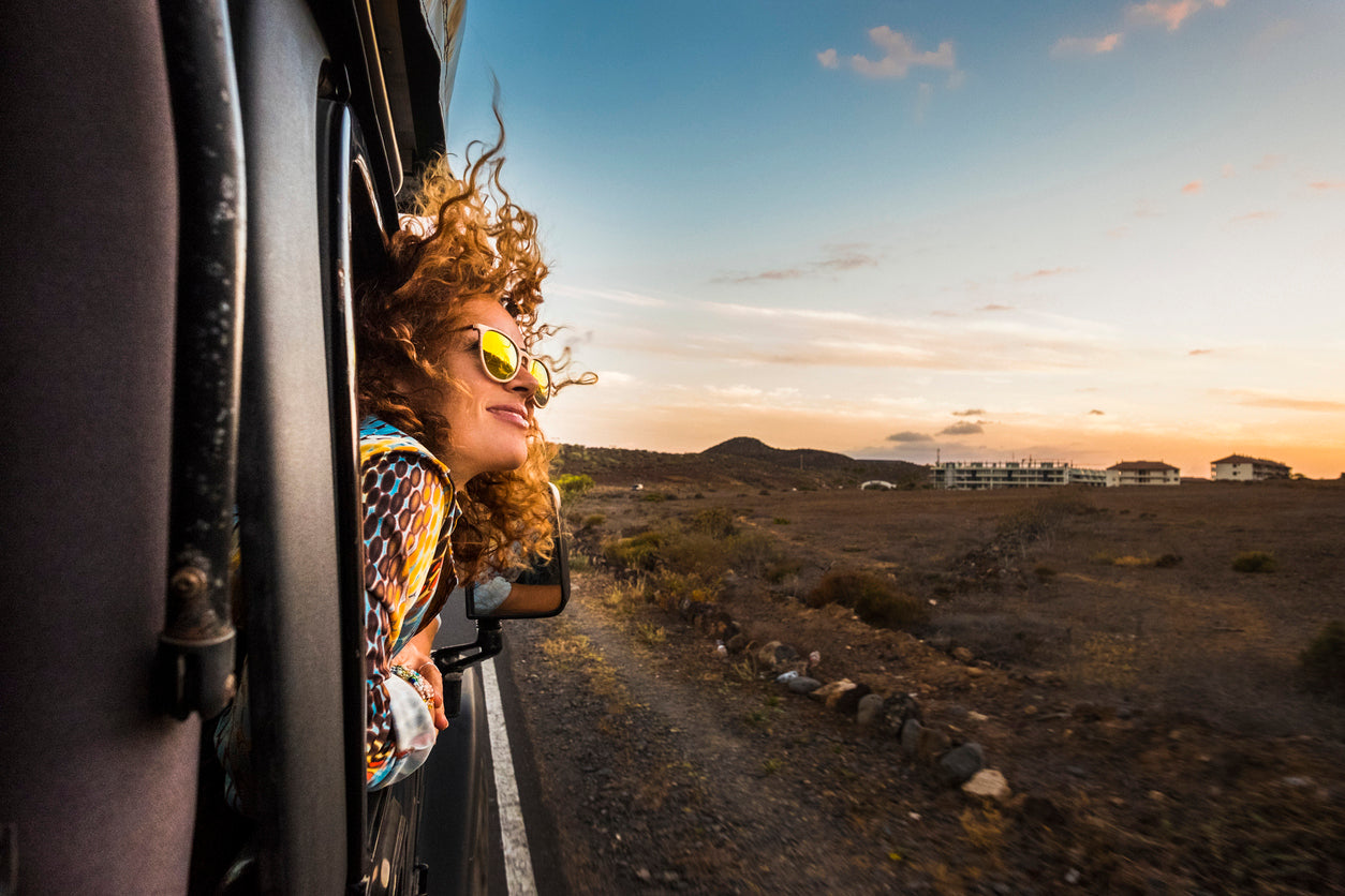 woman-wearing-sunglasses-putting-head-out-window-of-vehicle-on-sunny-day